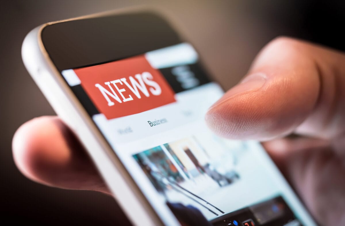 Online news in mobile phone. Close up of smartphone screen. Man reading articles in application. Hand holding smart device. Mockup website. Newspaper and portal on internet.