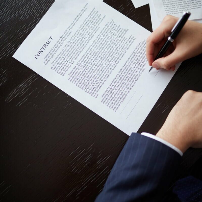 Image of businessman hand with pen signing contract at workplace