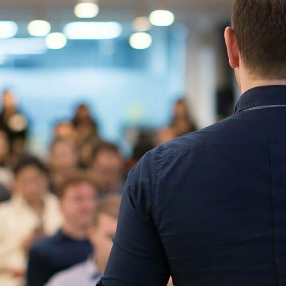 close up photo of a speaker's back facing his audiences